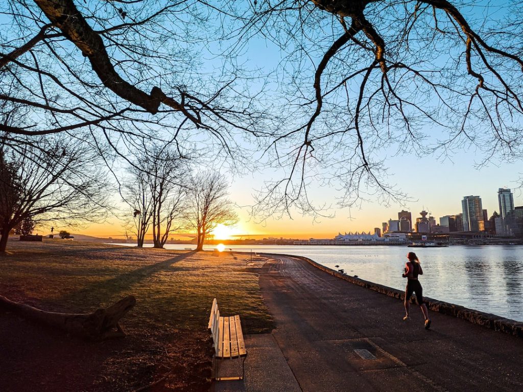 woman running on Stanley Park seawall at sunset